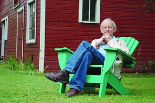 UU Poet Ted Kooser sitting in a chair on a lawn