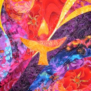 detail of a colorful art quilt with a flaming chalice design in the center