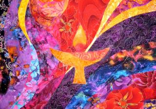 detail of a colorful art quilt with a flaming chalice design in the center